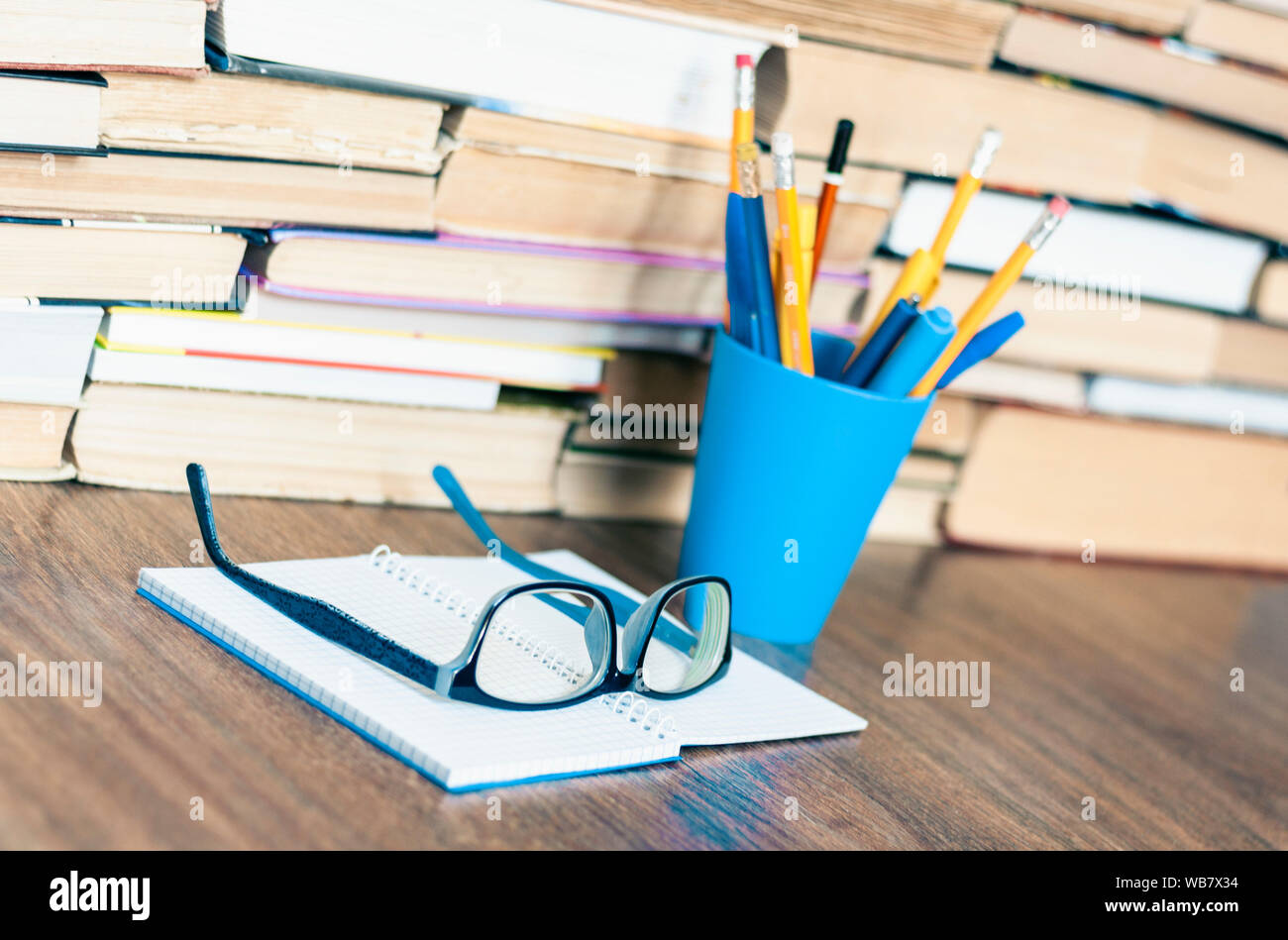 https://c8.alamy.com/comp/WB7X34/stack-of-old-book-pens-and-pencils-in-holder-open-notebook-and-glasses-education-concept-background-many-books-piles-with-copy-space-for-text-WB7X34.jpg
