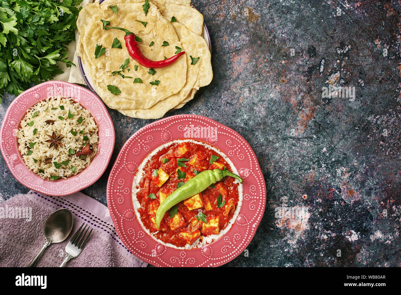 Paneer Makhani, Jeera Rice and paratha in pink plate on dark background