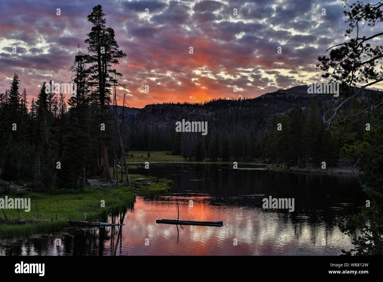 The setting sun lights up the clouds and reflects on Butterfly Lake along SR 150, the Mirror Lake Scenic Byway, in the Uinta Mountain Range, Utah, USA. Stock Photo