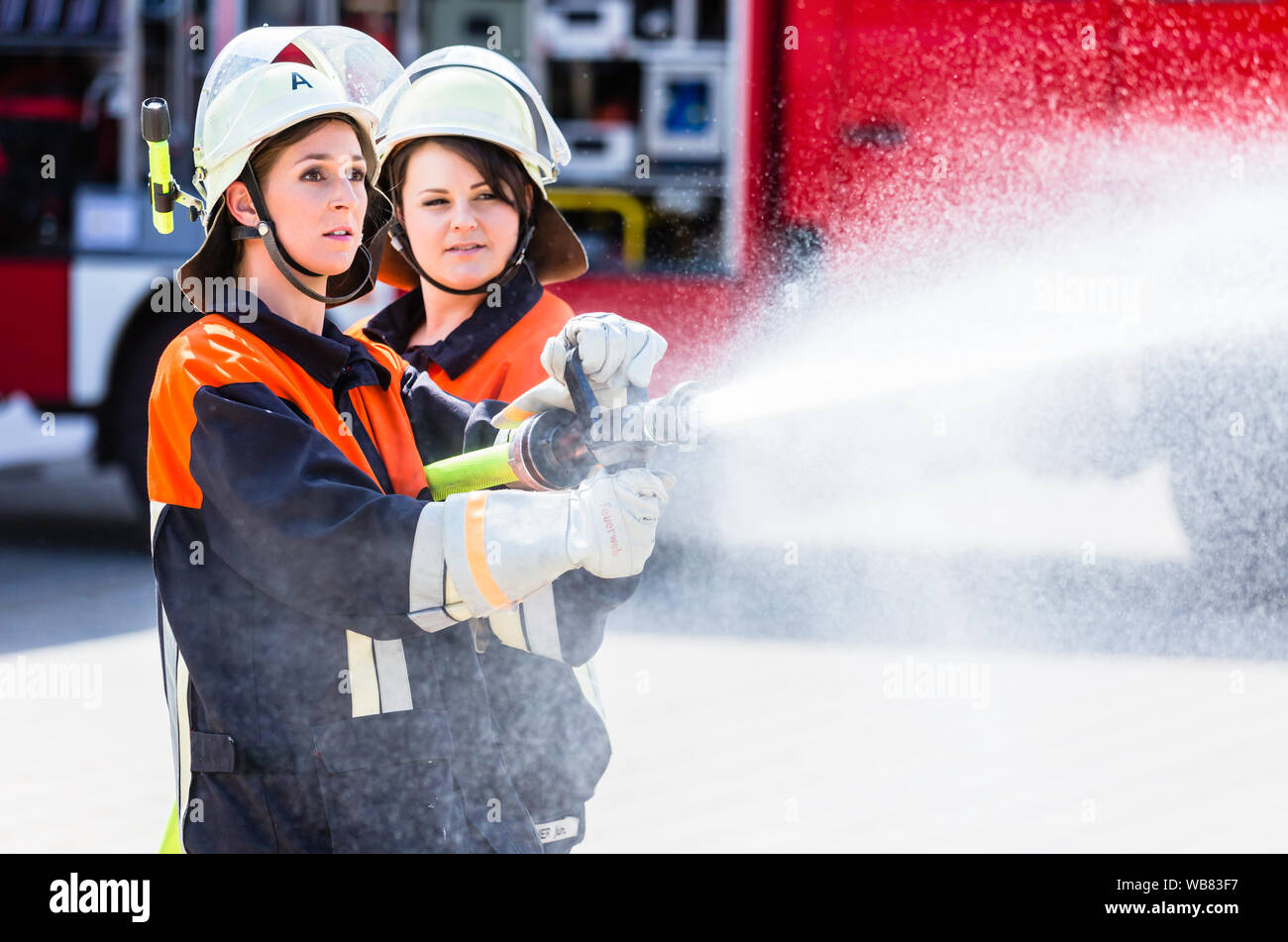 Female fire fighters spouting water to extinguish Stock Photo