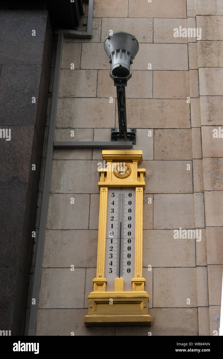 Moscow, Russia - August 2019. Photo of street design. An electric lamp on one of the buildings above a gilded street thermometer showing the temperatu Stock Photo