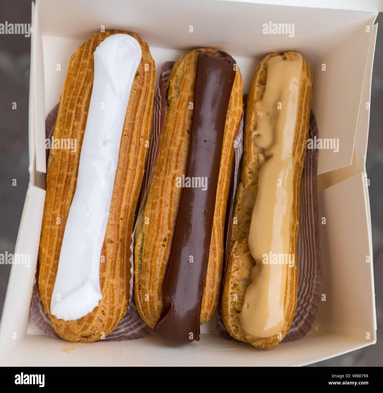 Colorful Eclairs In The Box. Eclairs Laying Inside White Boxes. Eclair Cakes With Scalded Carmel And Coffee Butter Cream. Stock Photo