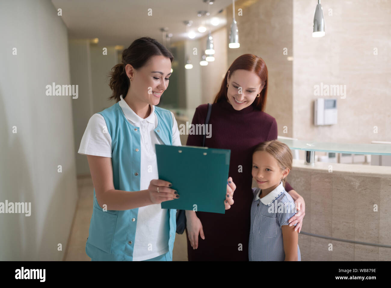 Daughter and mother listening to receptionist before going to dentist Stock Photo