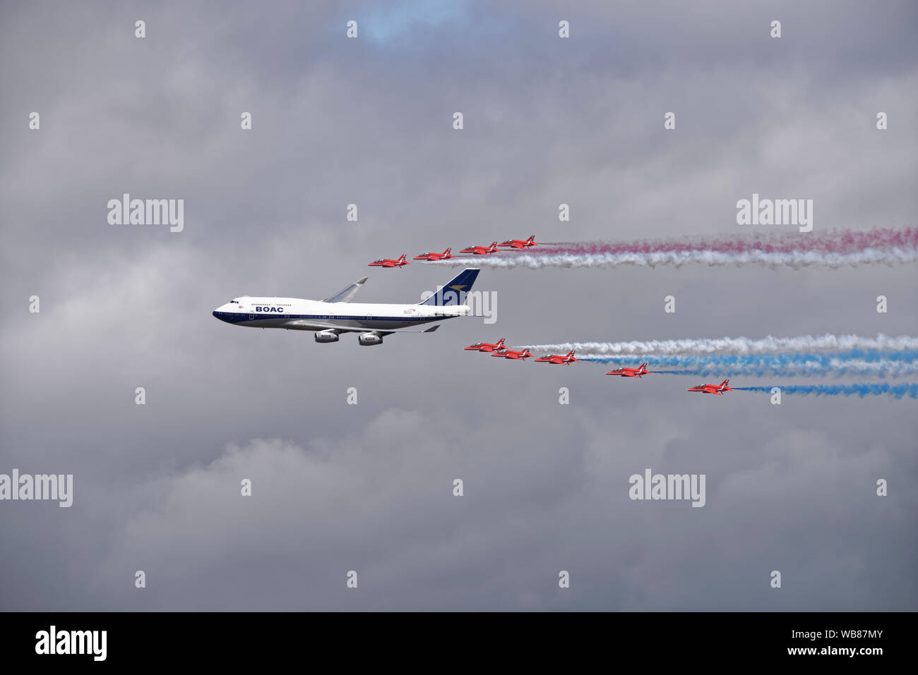 The British  Red Arrows aerobatic display team celebrate British Airways 100th birthday with a flypast in formation with a BOAC Boeing 747 airliner Stock Photo