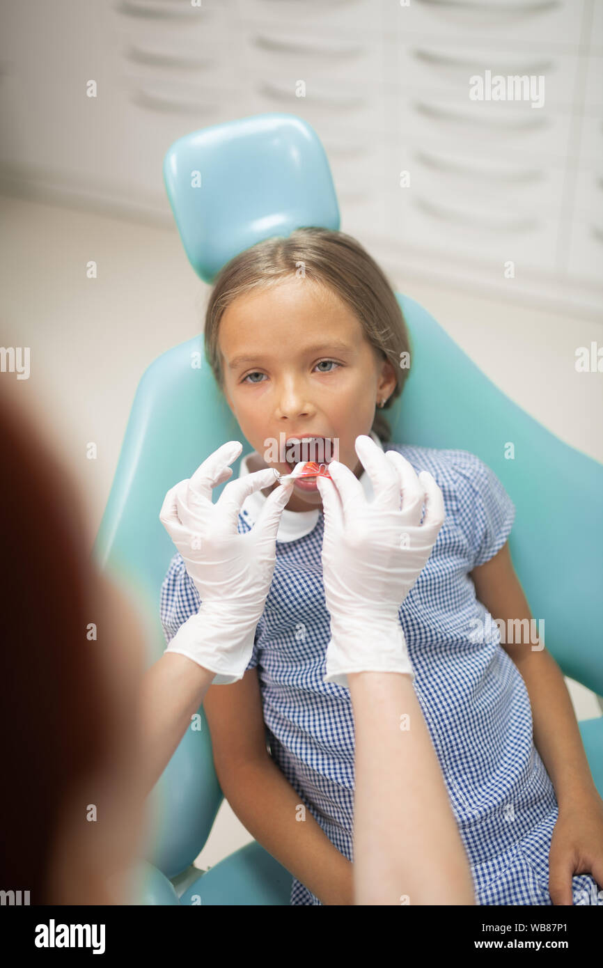 Girl opening mouth wide while dentist putting mouth guard inside Stock Photo