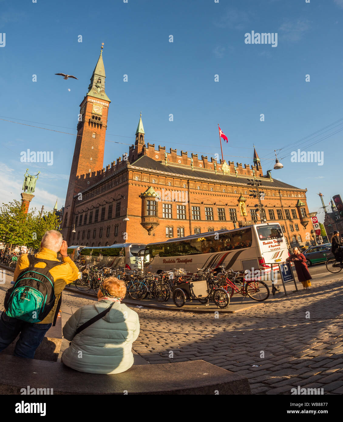 Copenhagen, Denmark - July 1, 2018: The building of Copenhagen's city hall in a rays of the sun during the sunset and the tourists making the pictures Stock Photo