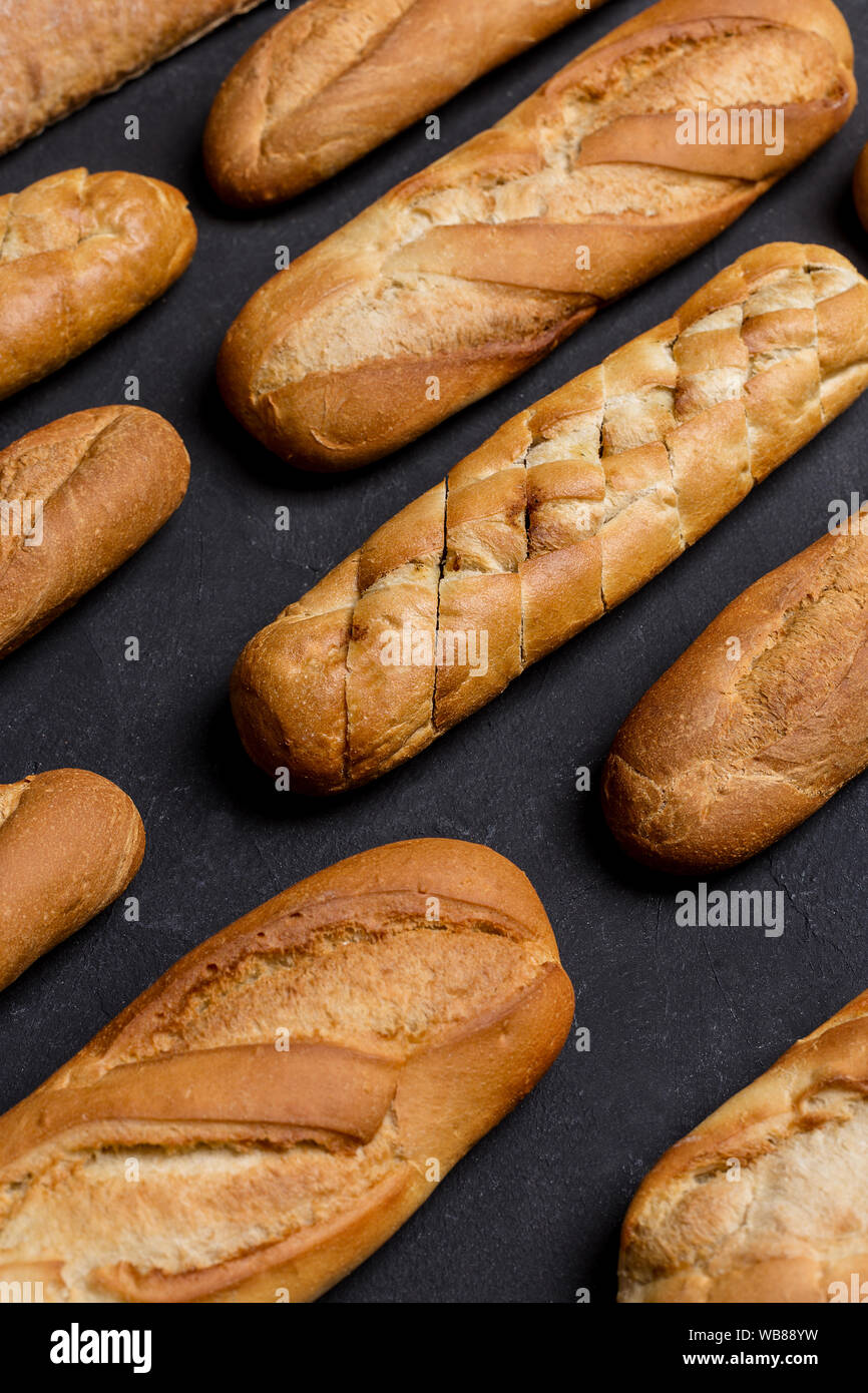 Close up different kinds of bread lay on black background. Banner for market shop Stock Photo