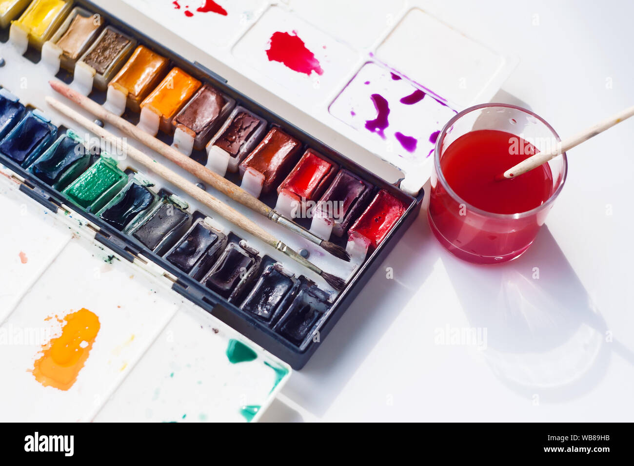 Paint brushes with gouache in cup isolated on white - Stock Photo