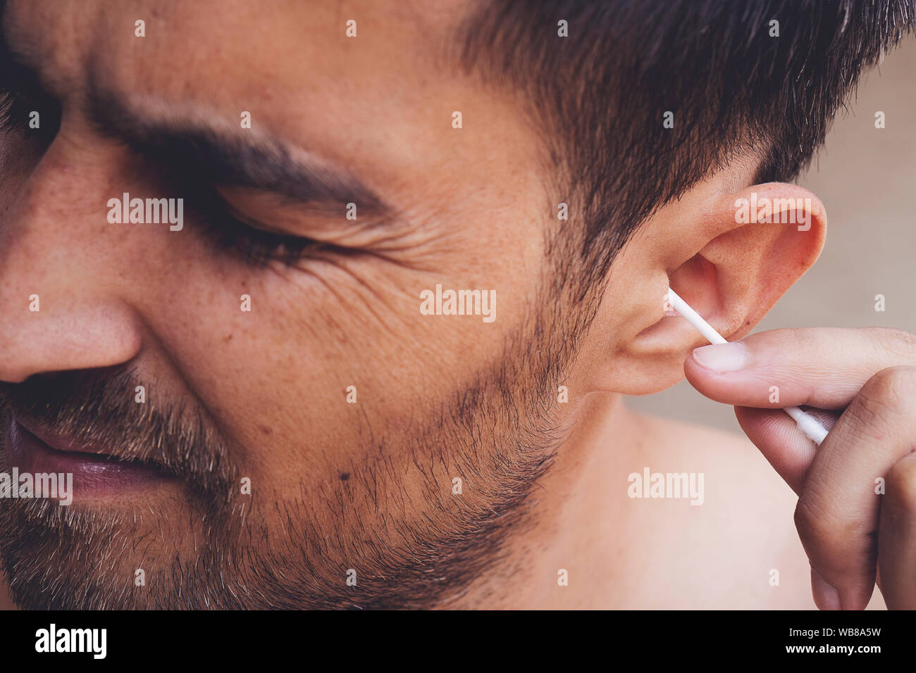 Man about to clean his ears using Qtip cotton swab. Hygiene essentials