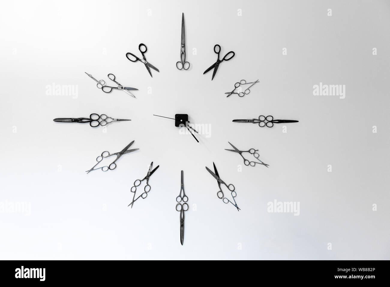 Wall clock made from scissors showing time on white wall background backdrop watch Stock Photo