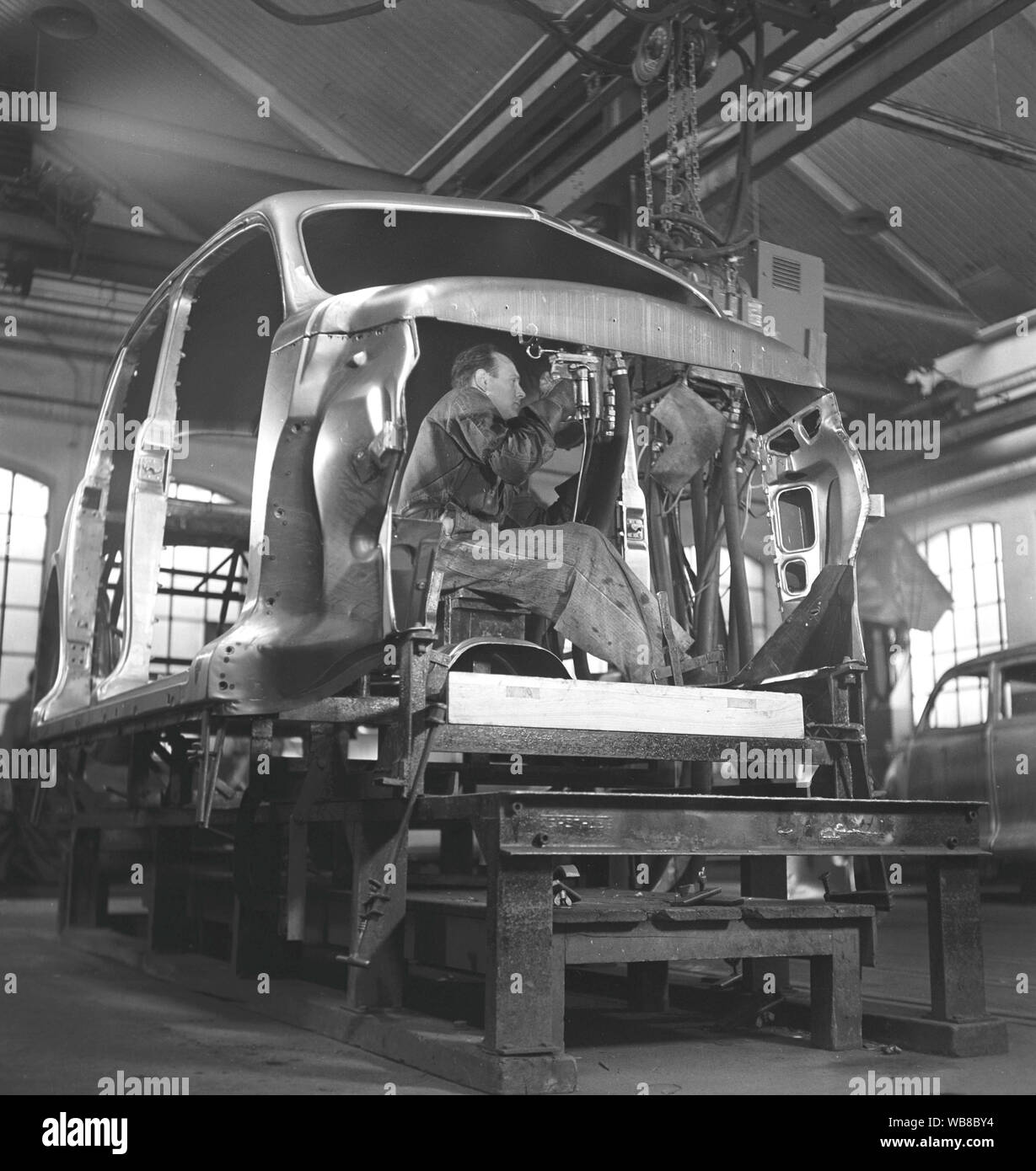 Car manufacturing in the 1940s. A worker in a car assembly line use an hydraulic tool to mount parts of the car together. After World war II several companies in Sweden recieved cars in parts and assembeled them. It was less cost to import car parts then the whole car. Sweden 1948. Kristoffersson ref AP89-2 Stock Photo
