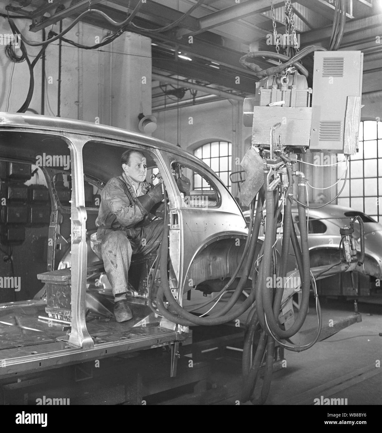 Car manufacturing in the 1940s. A worker in a car assembly line use an hydraulic tool to mount parts of the car together. After World war II several companies in Sweden recieved cars in parts and assembeled them. It was less cost to import car parts then the whole car. Sweden 1948. Kristoffersson ref AP89-4 Stock Photo