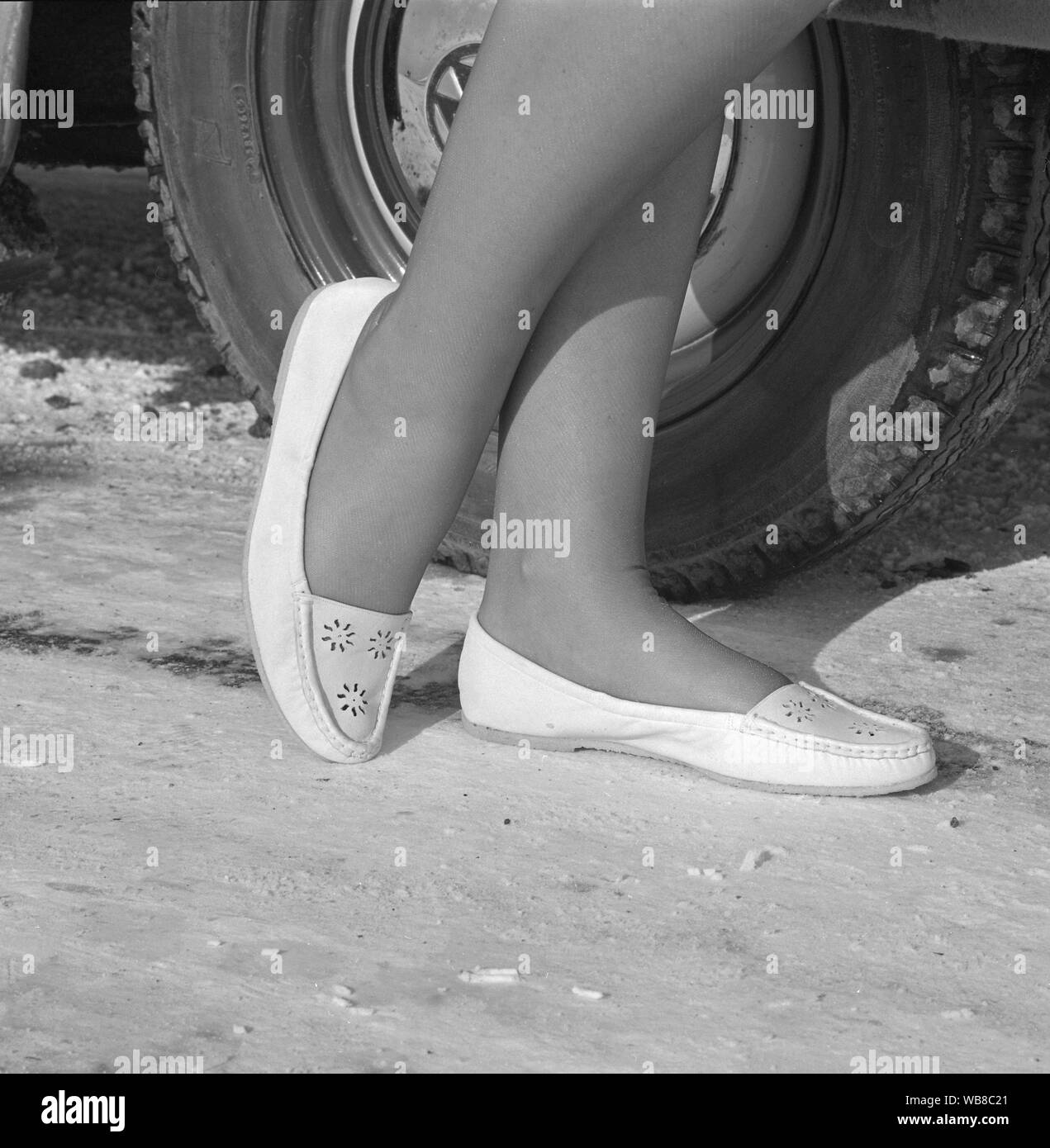 Driving in the 1960s. A woman demonstrates a new pair of shoes especially designed to be comfortable when driving the car. Sweden 1962 Stock Photo