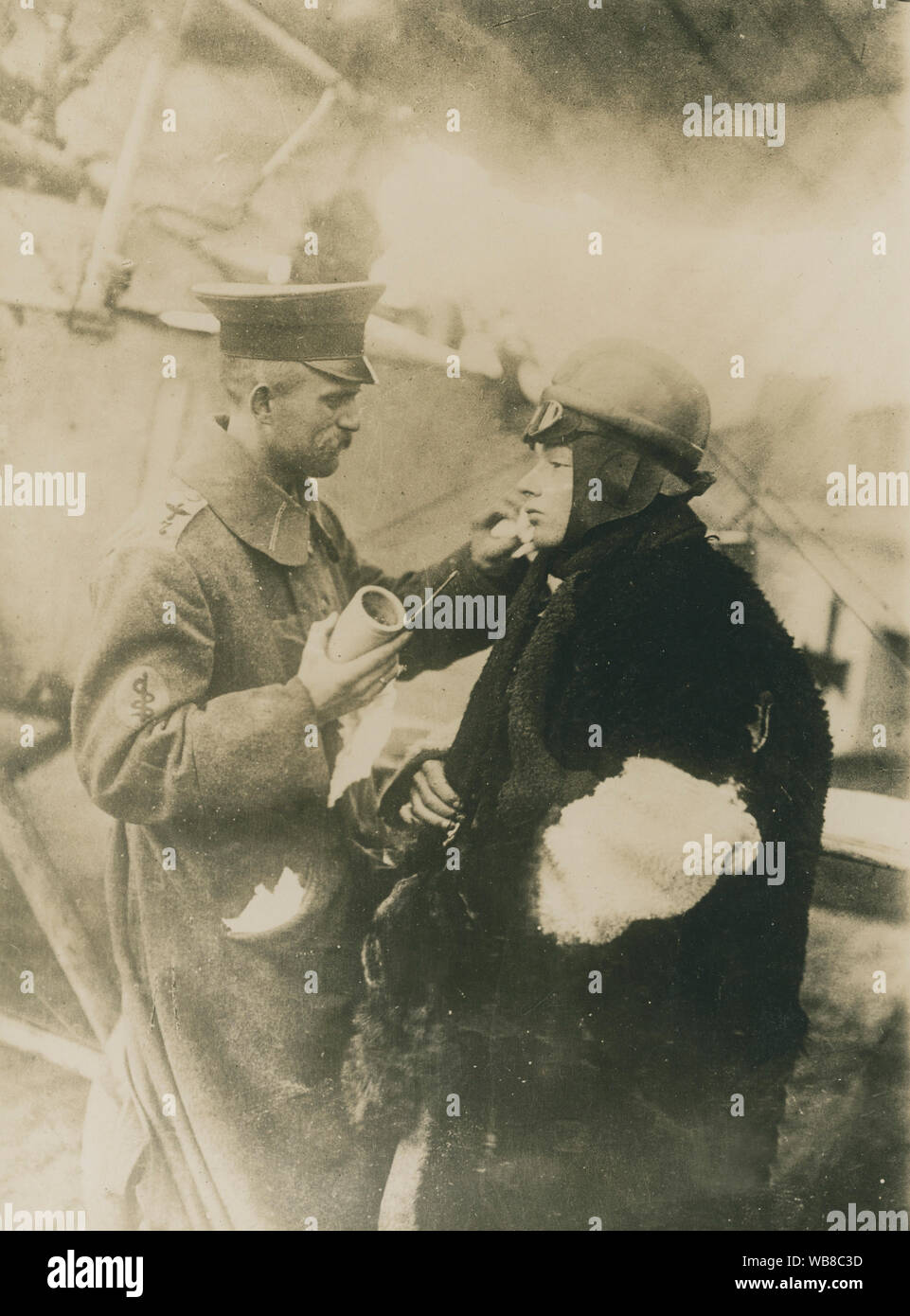 First World War 1914-1918. A pilot is being prepared for a flight mission. He is dressed in a warm coat. A man is putting on an ointment on the pilot's face that is somewhat protective against the cold wind when he sits in the open cockpit of the aircraft. Stock Photo