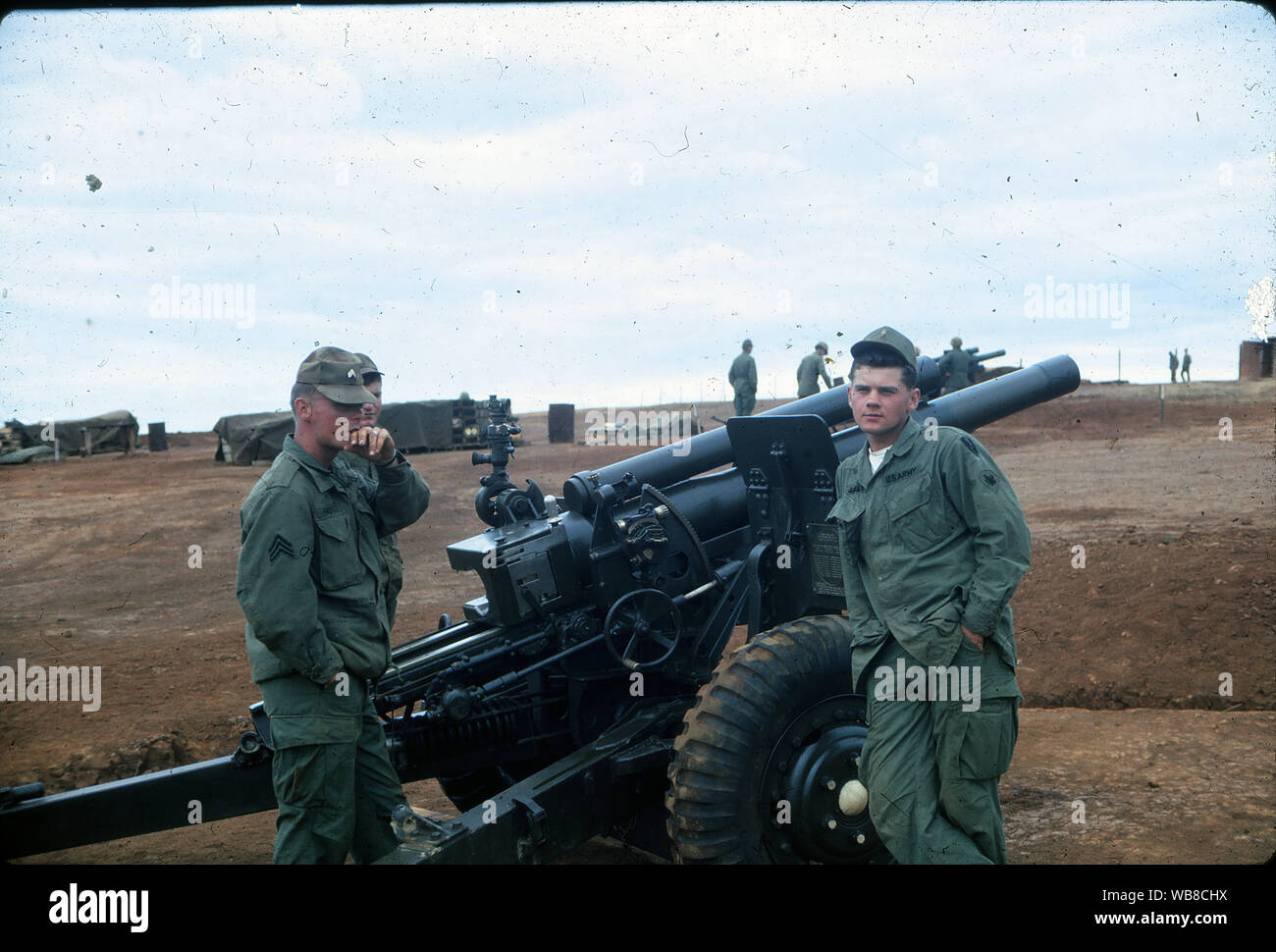 US Army servicemen stand next to a Howitzer artillery gun at a base during the Vietnam War in February of 1967. Stock Photo