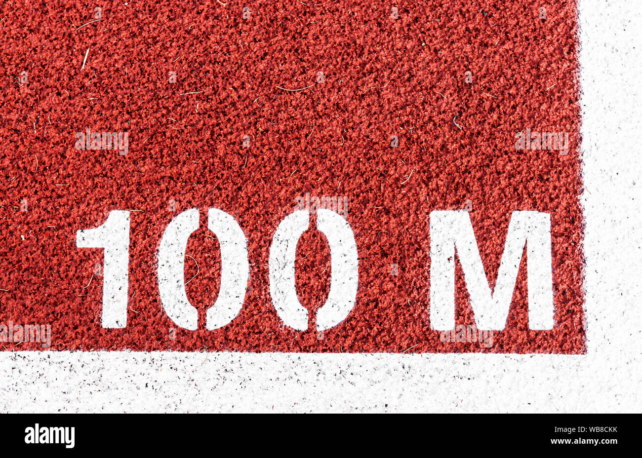 100 M is painted at the start line of the dash on a red track. Stock Photo