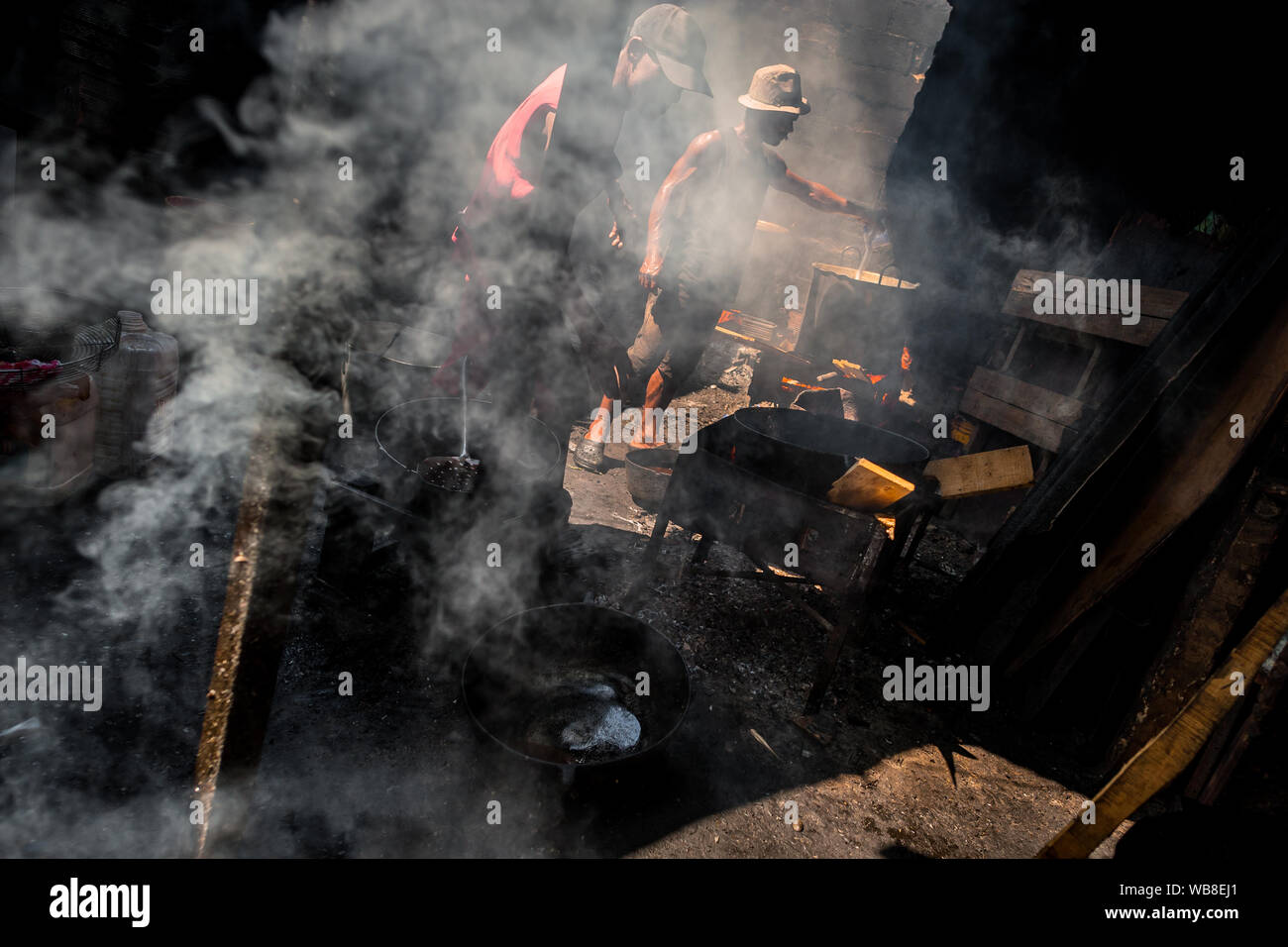 Afro-Colombian cooks fry fish in boiling oil in a street restaurant in the market of Bazurto in Cartagena, Colombia. Stock Photo