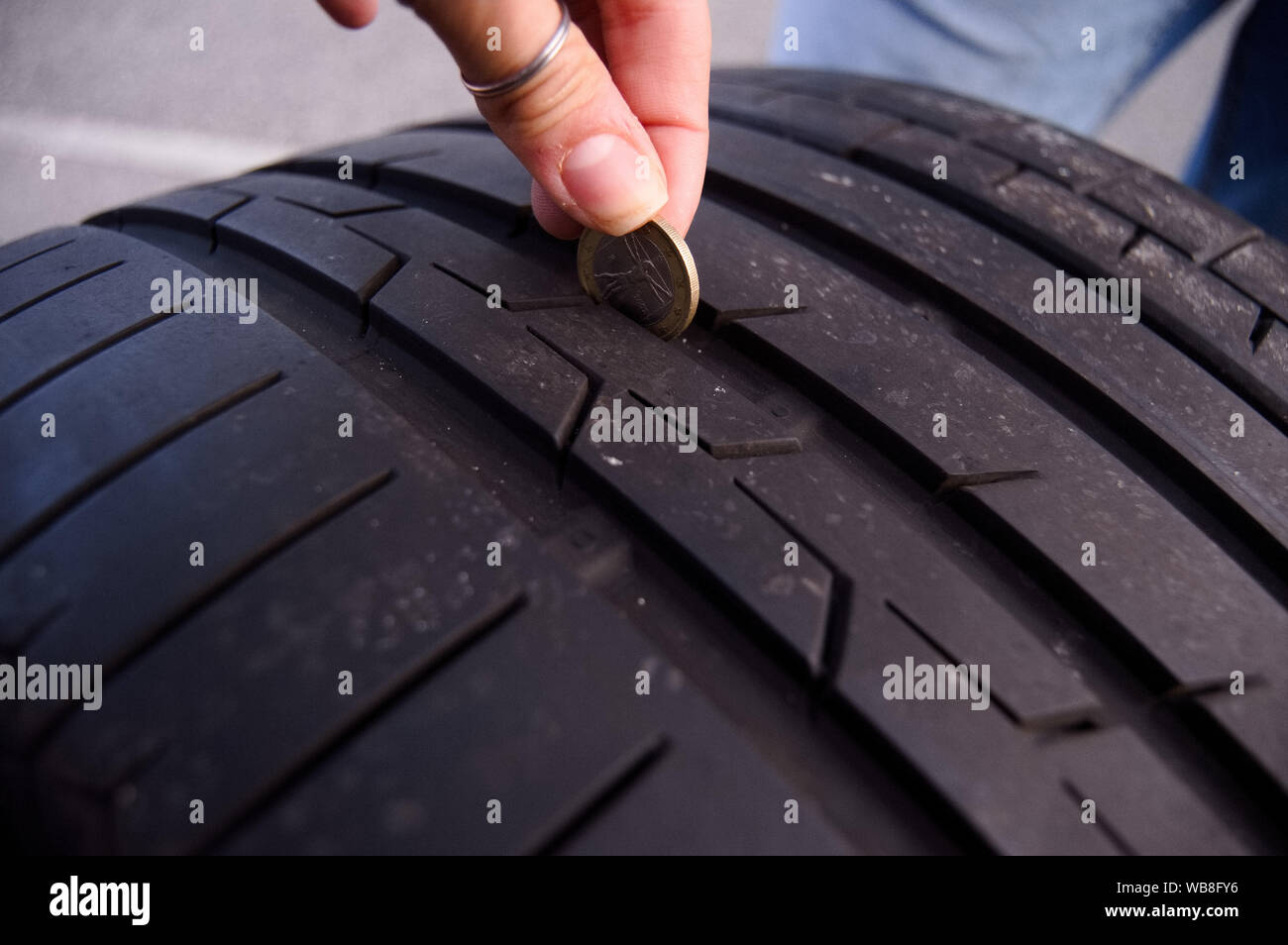FemaleMeasuring tire depth using a small coin Stock Photo Alamy