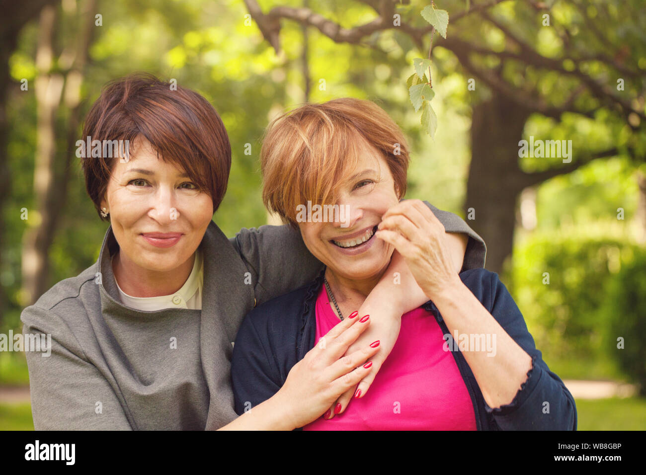 Two happy women walking in summer park, portrait Stock Photo - Alamy