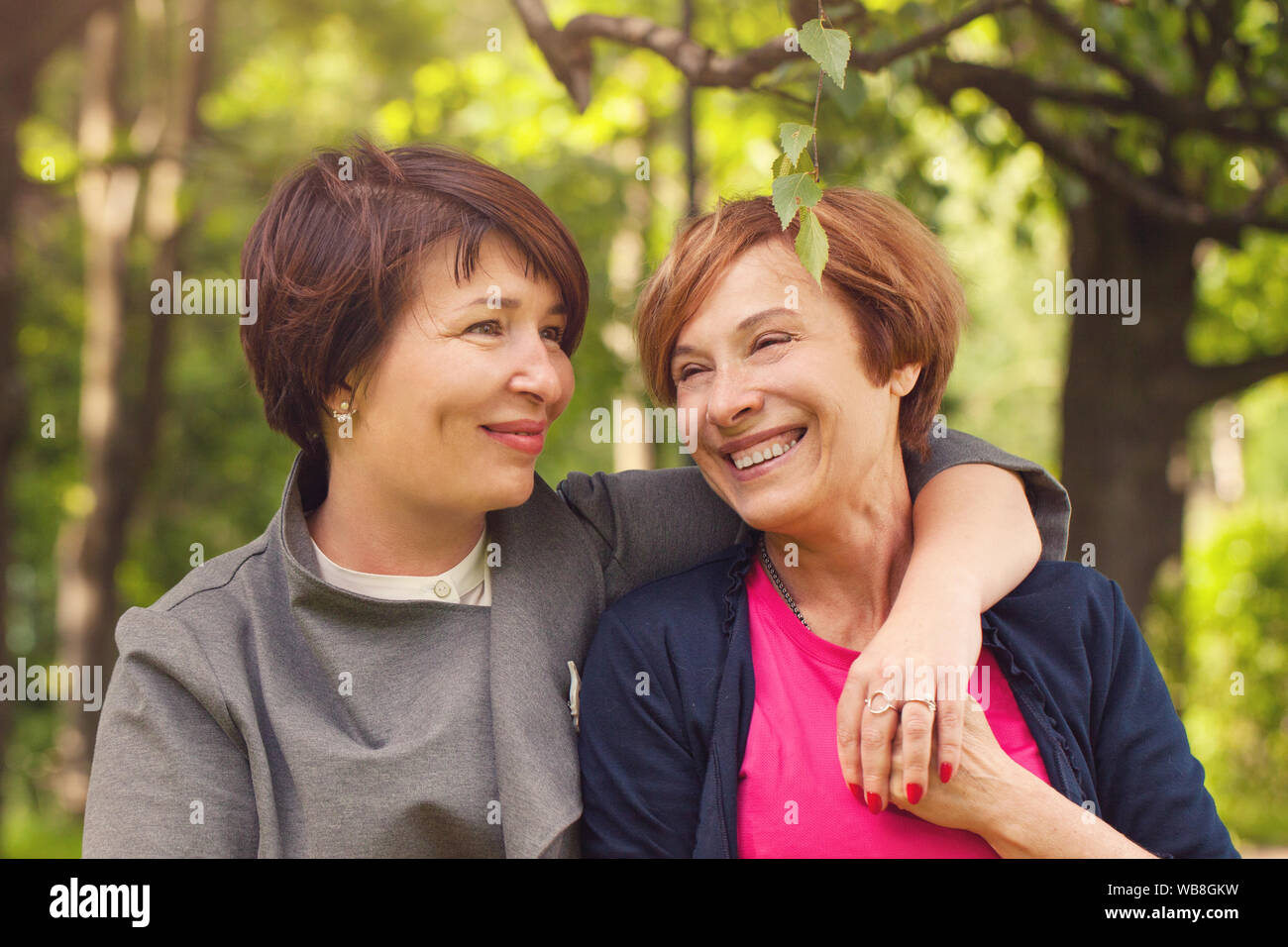 Two happy women walking in summer park, portrait Stock Photo - Alamy