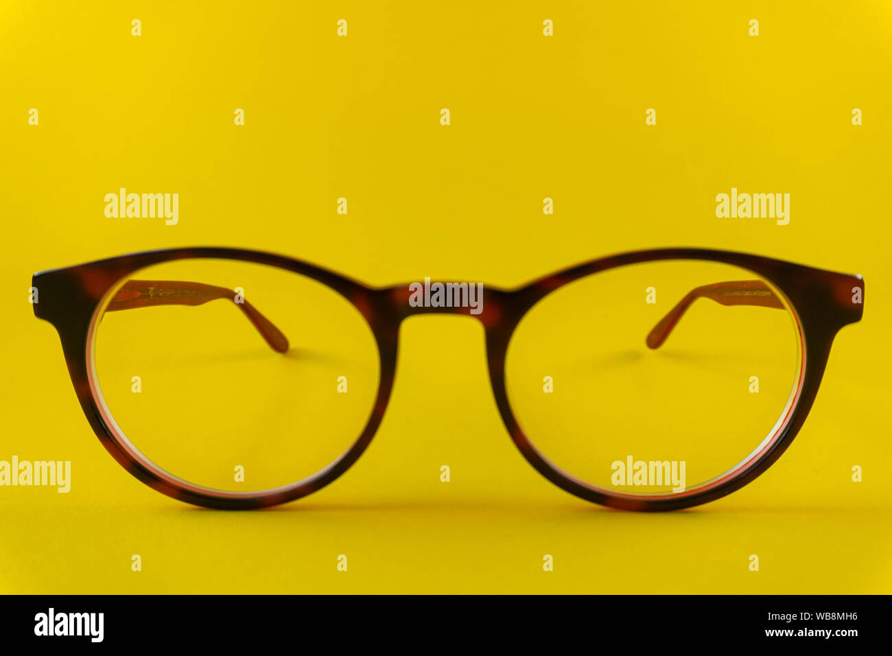 Brown-red, round glasses on yellow background Stock Photo