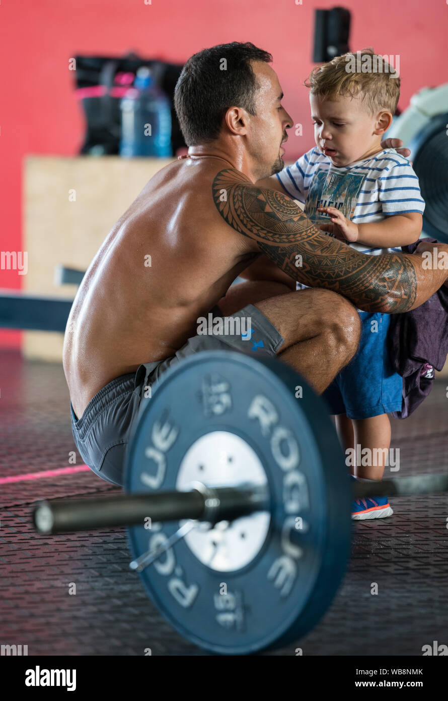 A mixed race athlete is jugging a mixed race child in the gym after weightlifting competition Stock Photo
