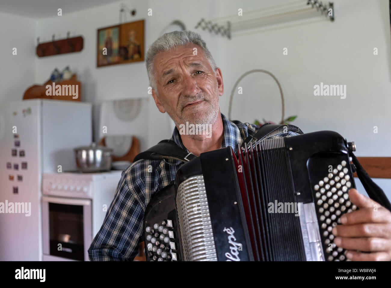 Serbia, July 20th 2019: Portrait of a local man playing harmonica and singing at his home in Village Solotuša Stock Photo