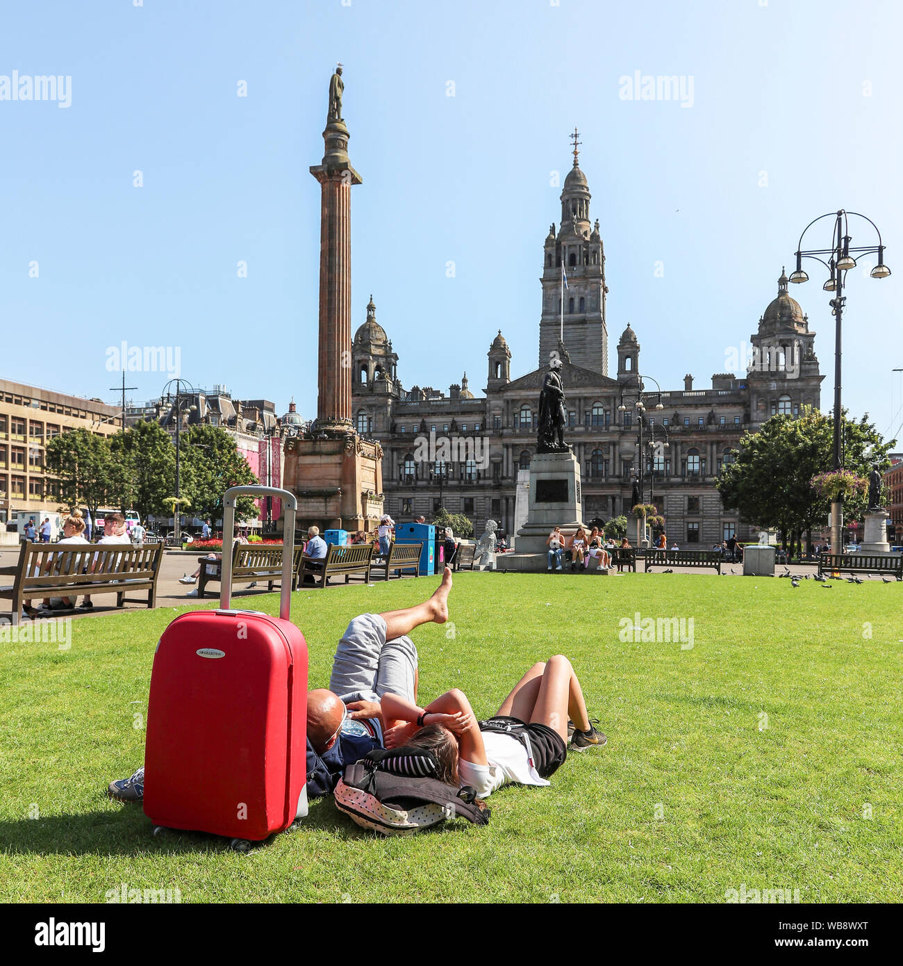 Glasgow, Scotland, UK. 25 August 2019. As temperatures soar to over 26C in Glasgow after days of rain and cold wind, people flock to the city's open spaces of George Square and the Botanic Gardens to take advantage of late summer sun on this August Bank Holiday, to top up their tans and relax. Credit: Findlay/Alamy Live News Stock Photo