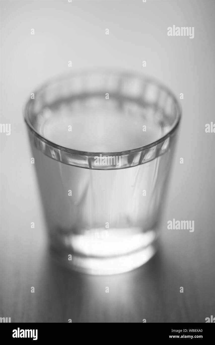 glass full of water on the table, selective art focus, bw Stock Photo