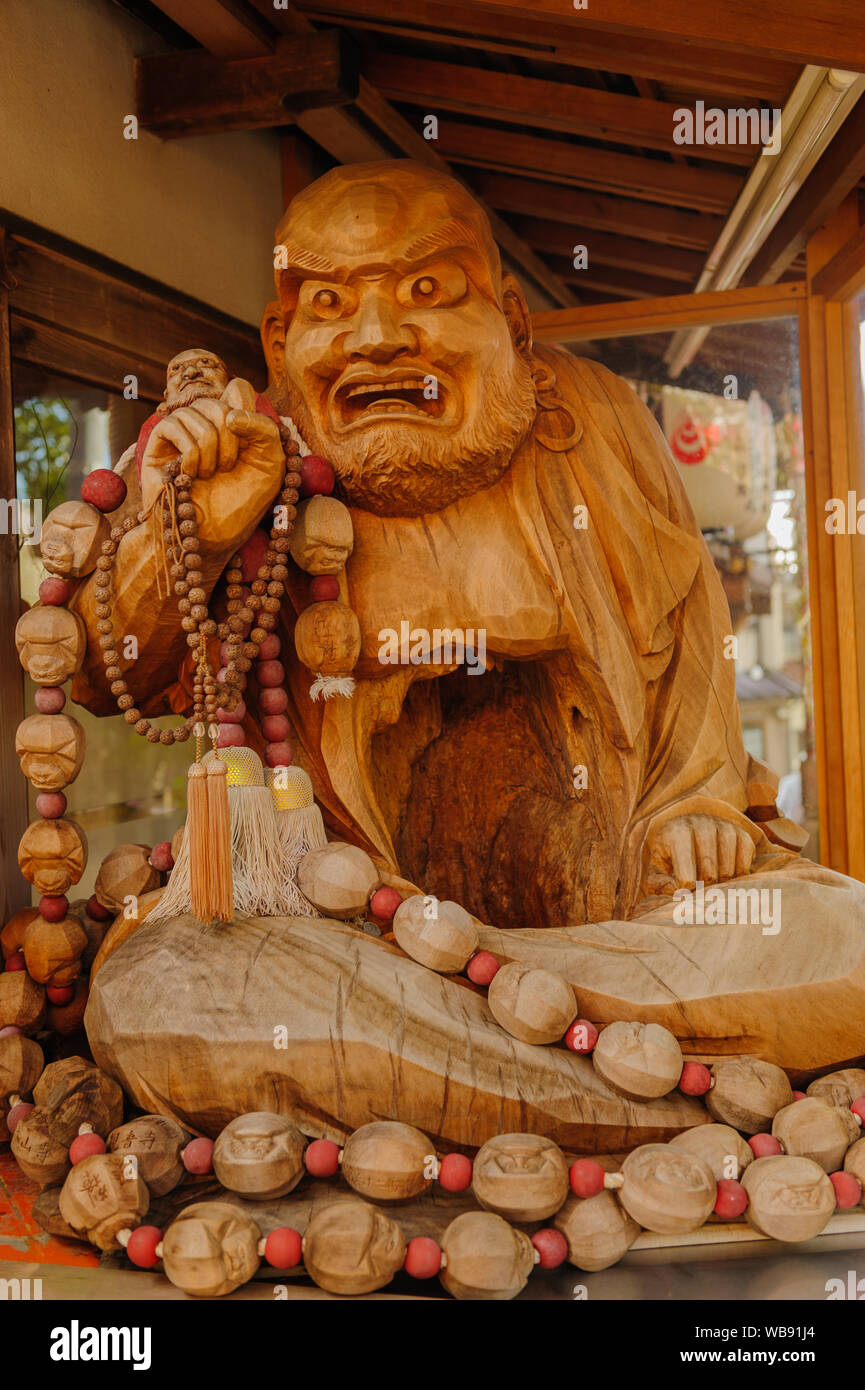 Carved wooden statue of an angry looking monk with a prayer beads in his hand reveals rich details of traditional artwork, Kyoto Japan November 2018 Stock Photo