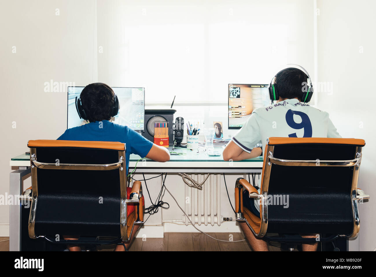 Madrid, Spain - August 23, 2019: Teenagers playing Fortnite video game and CSGO Counter Strike on PC. Fortnite is an online multiplayer video game dev Stock Photo