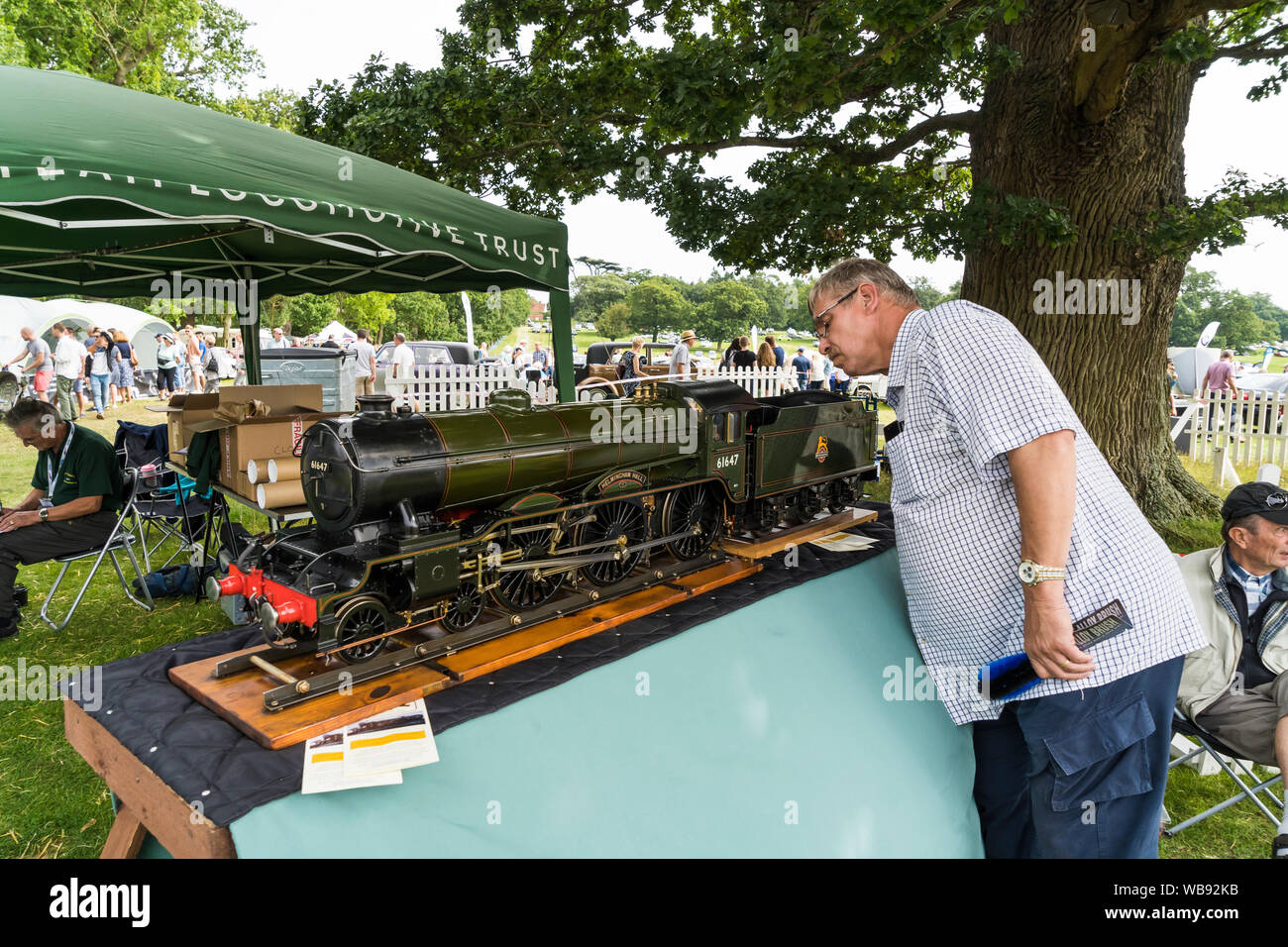 Visitor inspecting craftsmanship in 5 inch gauge model of LNER Class B17 4-6-0 Express passenger locomotive Helmingham Hall at The Helmingham Festival Stock Photo