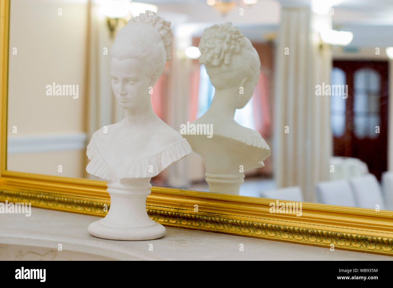 Beautiful figurine of the head of a girl with curly hair .On a shelf near the mirror. Stock Photo