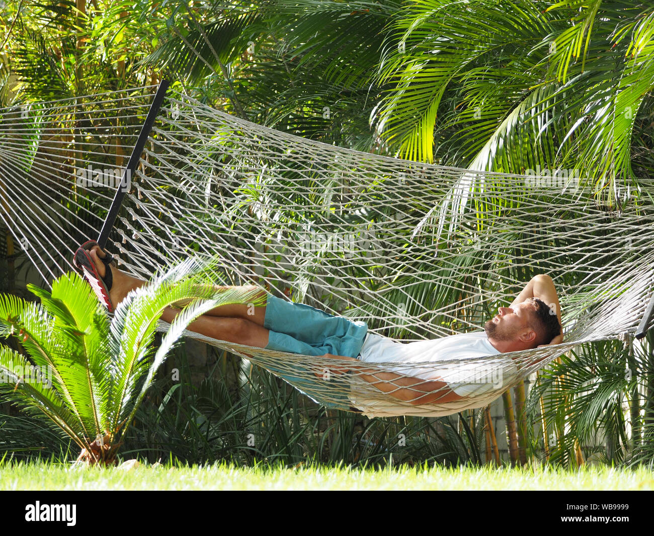 A man in a hotel lying in a hammock. Stock Photo