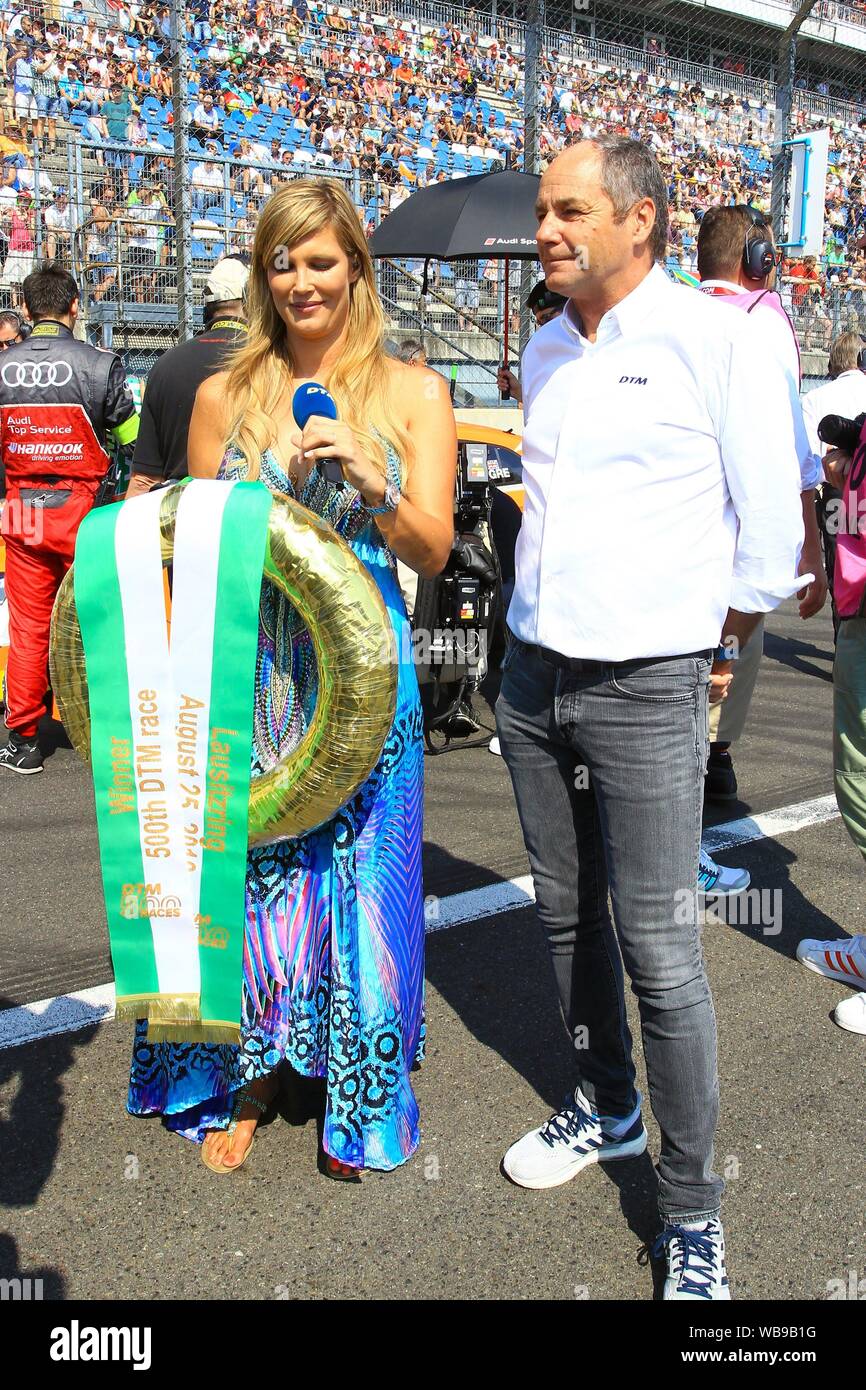 Klettwitz, Deutschland. 25th Aug, 2019. Klettwitz, Germany 23- 25 August 2019: DTM Lausitzring - Race 2 - 2019 TV presenter Verena Wriedt with the golden winners' crown for the 500th DTM race with the DTM boss Gerhard Berger | usage worldwide Credit: dpa/Alamy Live News Stock Photo