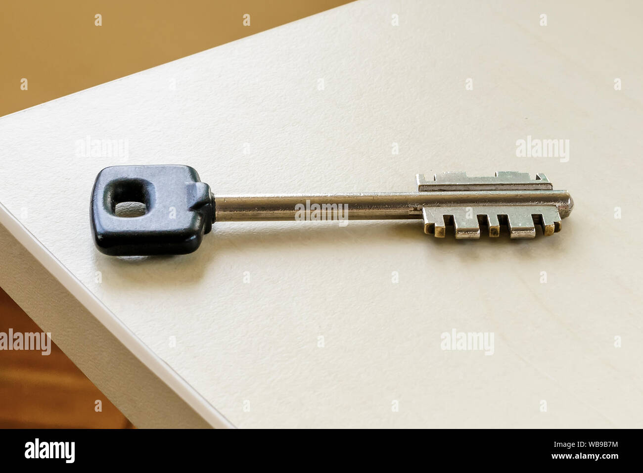 One large key with black head on a table in a room. To forget a key at home consept. Close-up. Stock Photo
