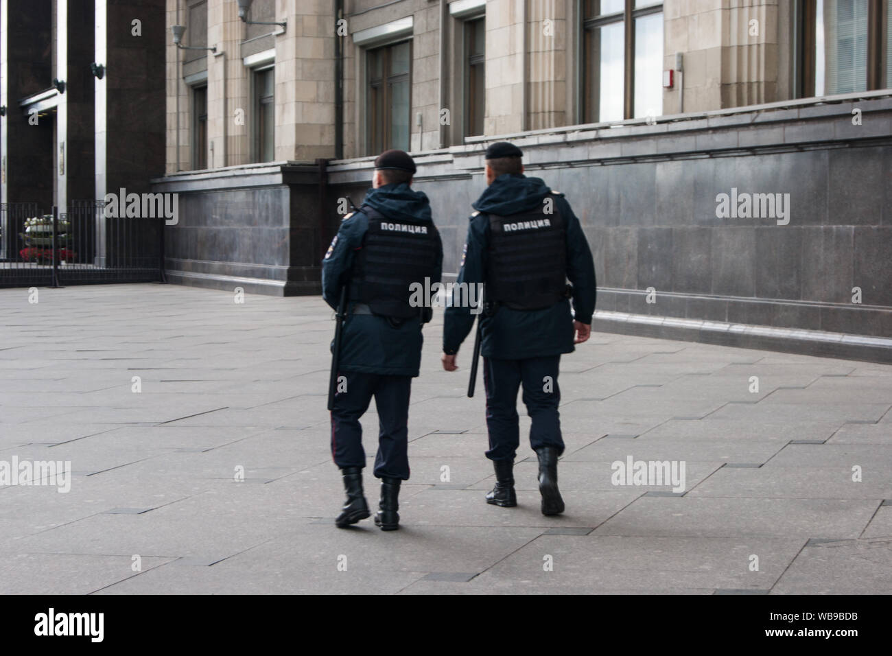 Police. In the photo, two policemen walk around the city in the direction from the viewer, we see their backs with the inscription in Russian - transl Stock Photo