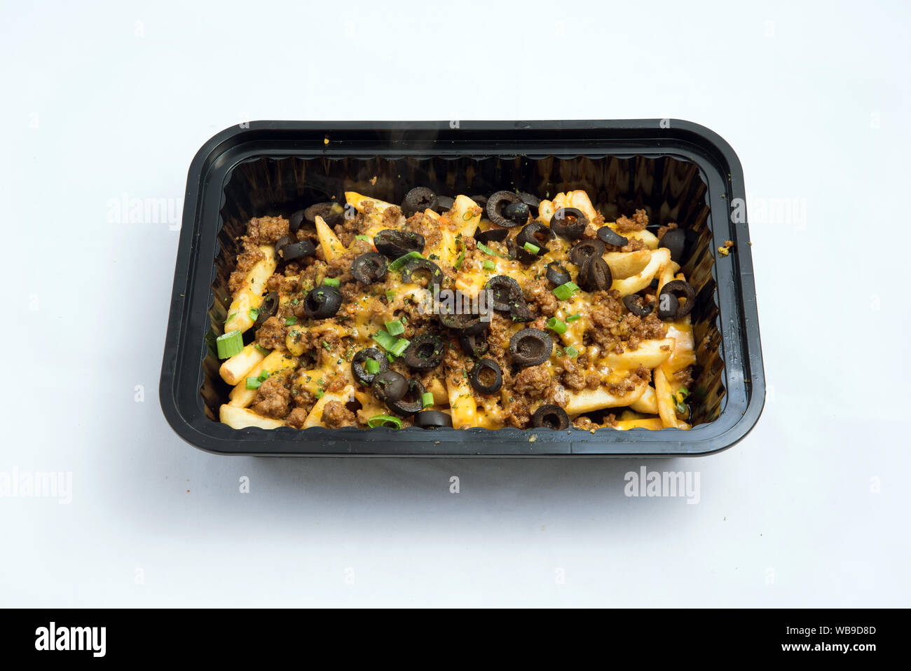 A high contrast Hero shot of a Take-Away Hot Loaded fries / chips with ground meat, olives, cheese, jalapeno, sauce & oregano, on a minimal white back Stock Photo