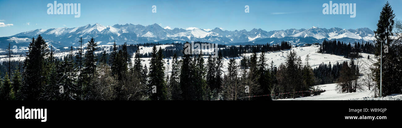 Wide panorama of Tatra mountains in winter,  viewed from Bania mountain in Bialka ski resort with ski chair lift. Far view of Kasprowy Wierch Stock Photo