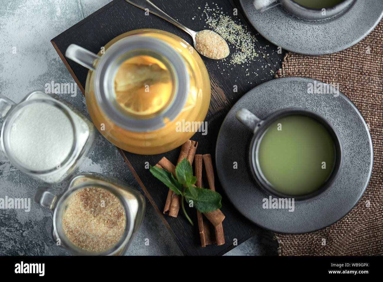 Transparent glass teapot with chitrus tea and cups, tea set on a wooden table. Close up, gray background, soft light Stock Photo