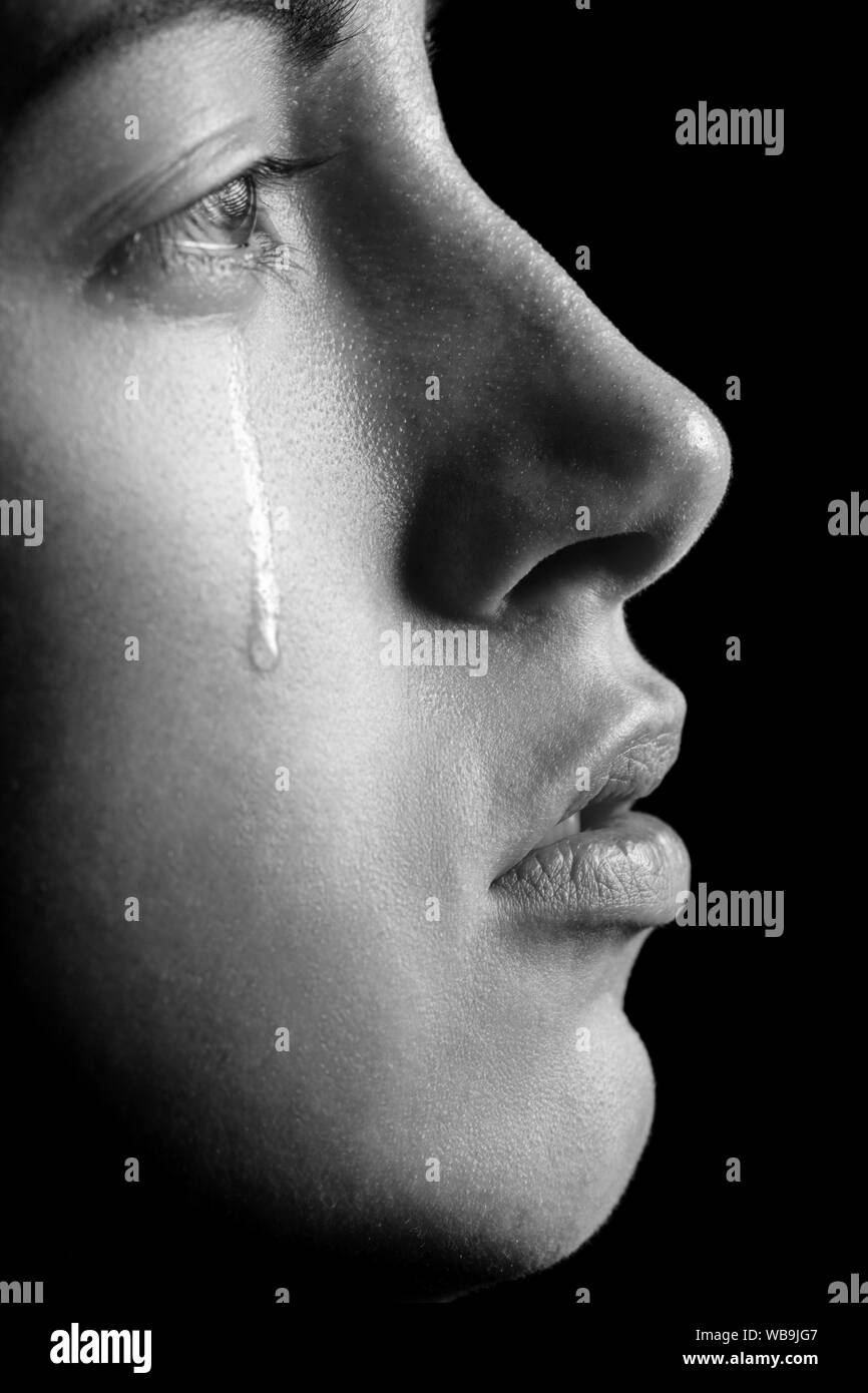 sad woman crying, looking aside on black background, closeup portrait, profile view, monochrome Stock Photo