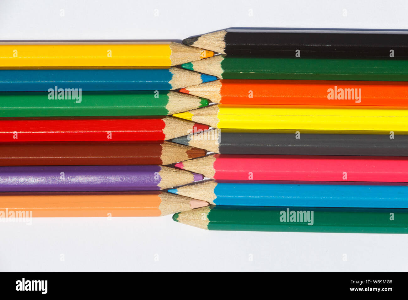 Multicolored wooden pencils interwoven on white background Stock Photo