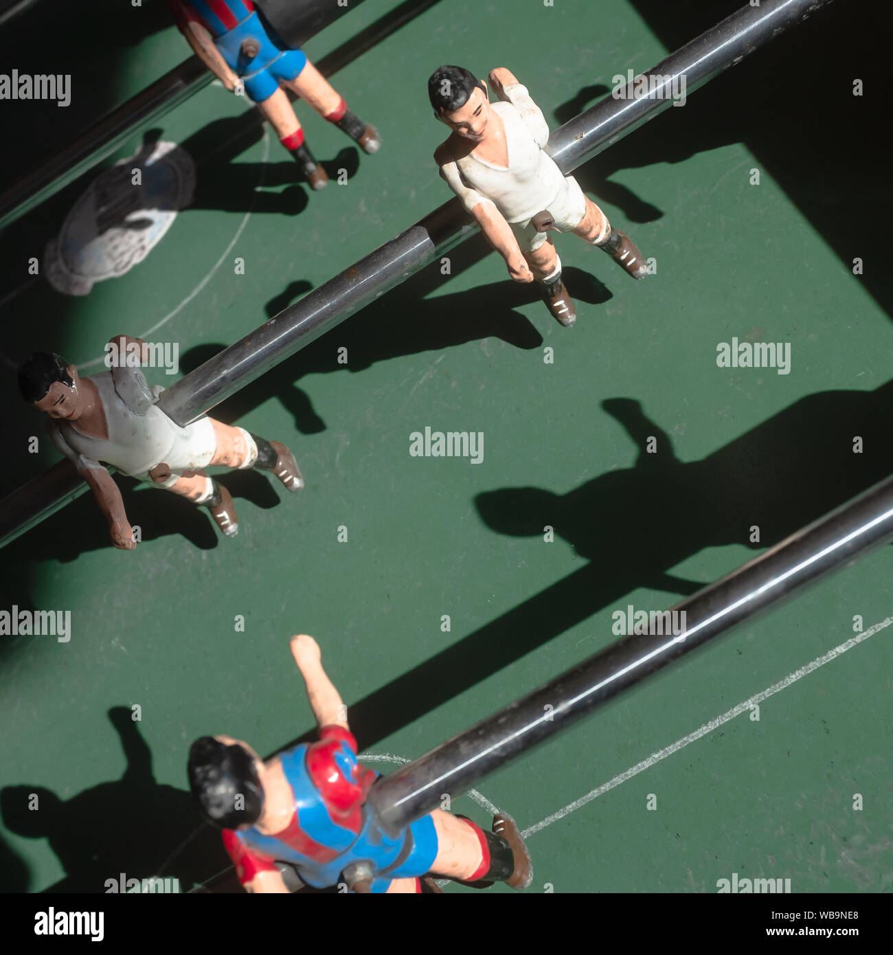 Figurines soccer players on an old foosball table. Directly above view. Rivalry and teamwork concepts. Stock Photo
