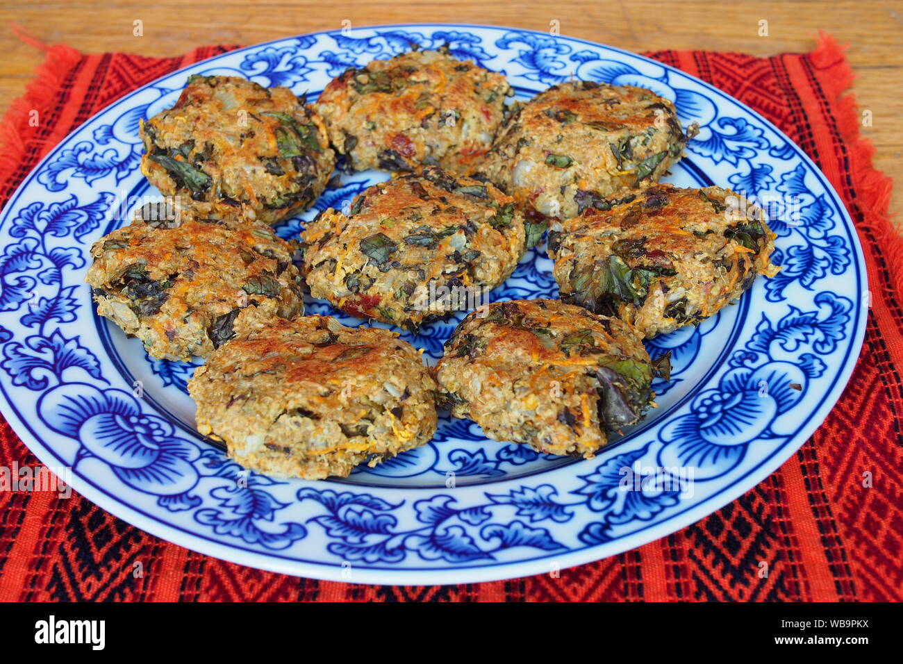 Eight quinoa patties on blue and white china on a red place mat. Veganalicious! Stock Photo