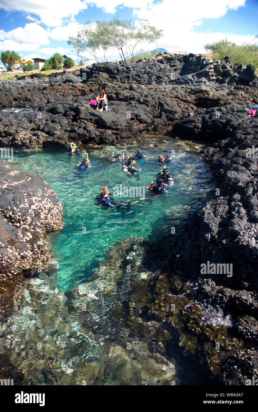 Scuba divers, receiving training in rock pool. The fringing reef at