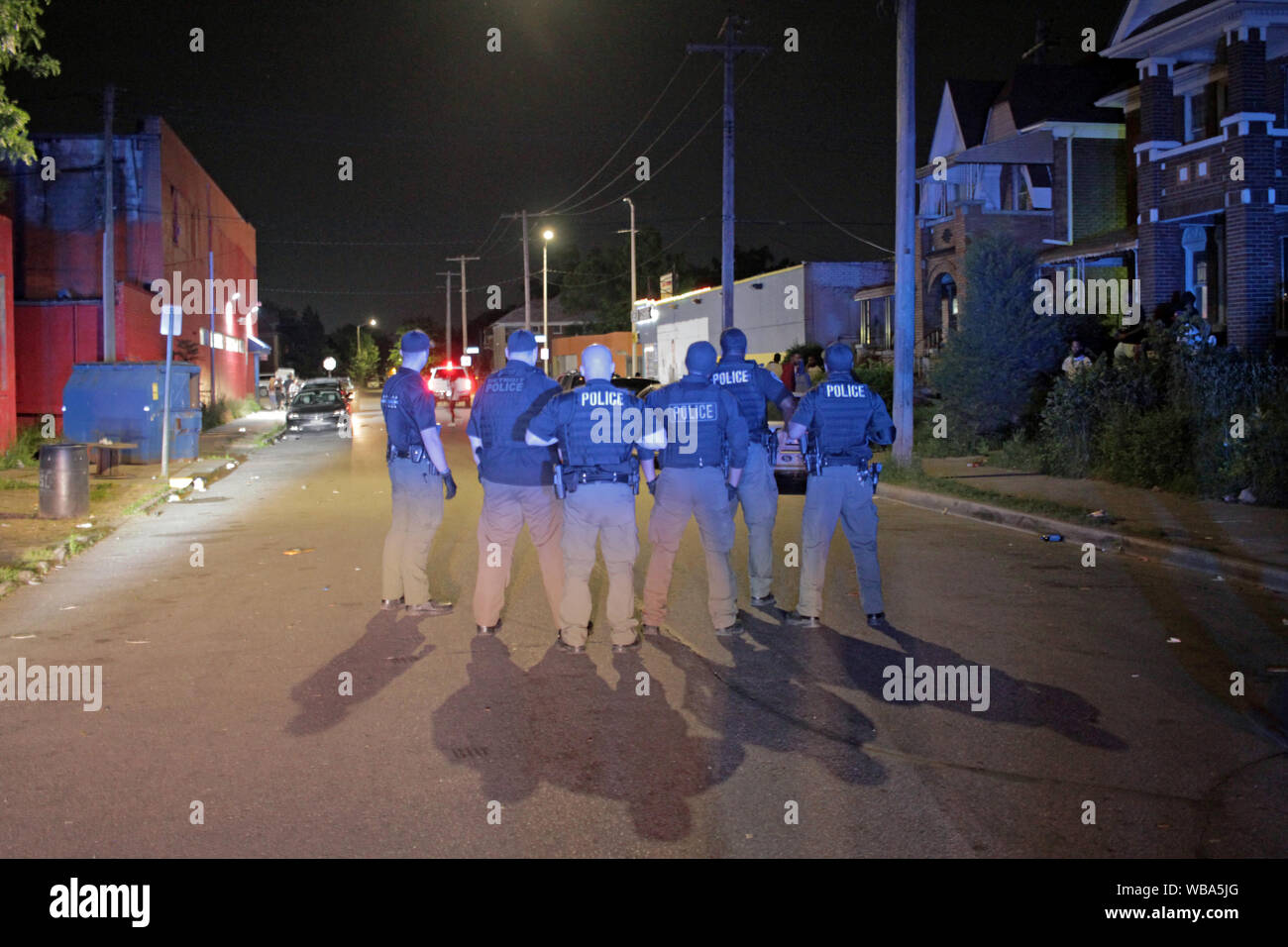 Group of Detroit police Special Ops officers stand in a street, trying