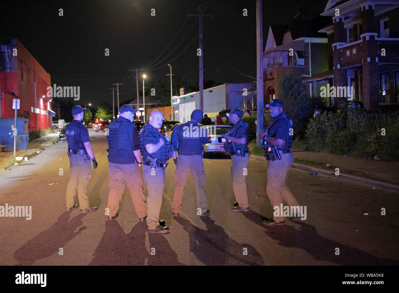 Group of Detroit police Special Ops officers stand in a street, trying