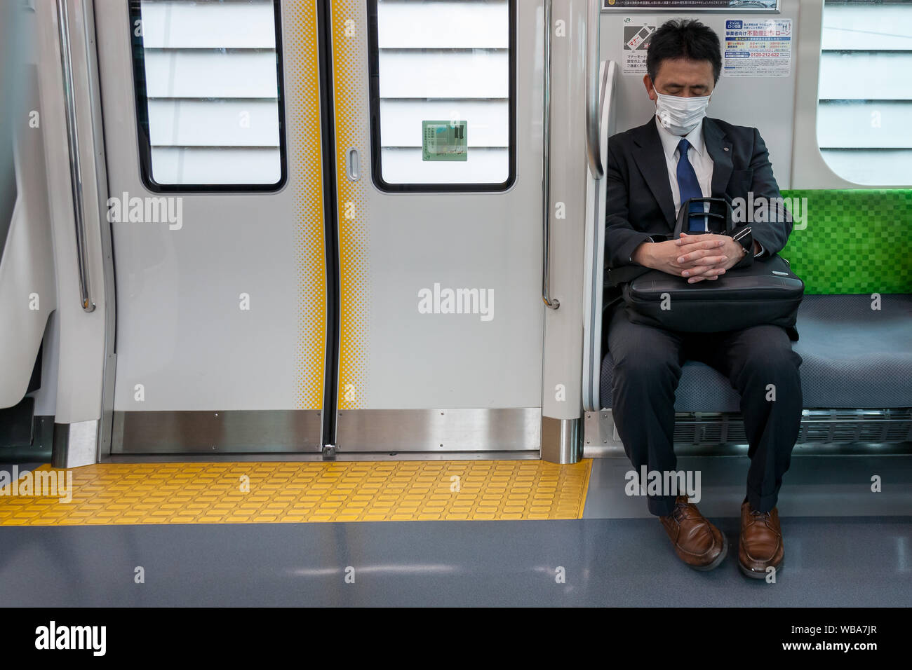 A Japanese male office worker or salaryman , wearing a face mask