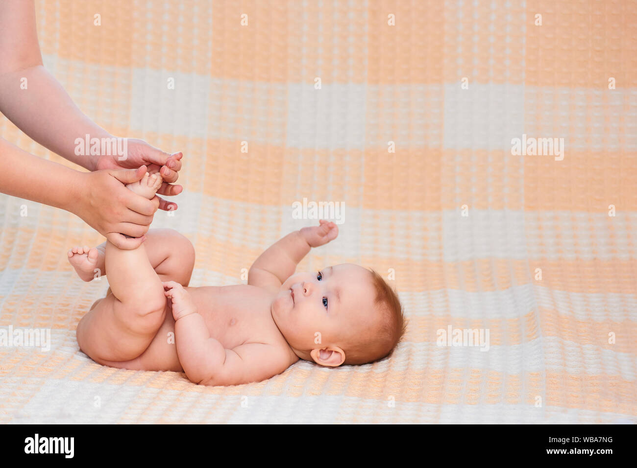 Baby massage. Mother massaging kid belly, baby laughing. Treatment of colic. Mother massaging her child. Family, newborn. Happy family. Body care. Stock Photo