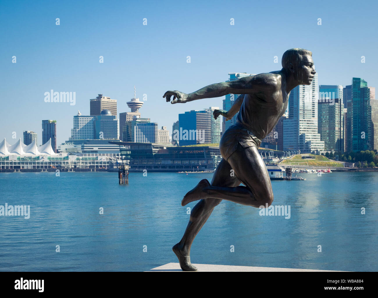 A sculpture of Canadian track and field star Harry Jerome in Stanley Park with Vancouver skyline. Vancouver, British Columbia, Canada Stock Photo